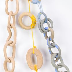 Detailed view of ceramic chains featuring yellow yarn, stoneware, and blue slip on the three different chain types.