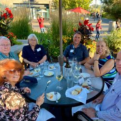 Several people gathering around a round table with food